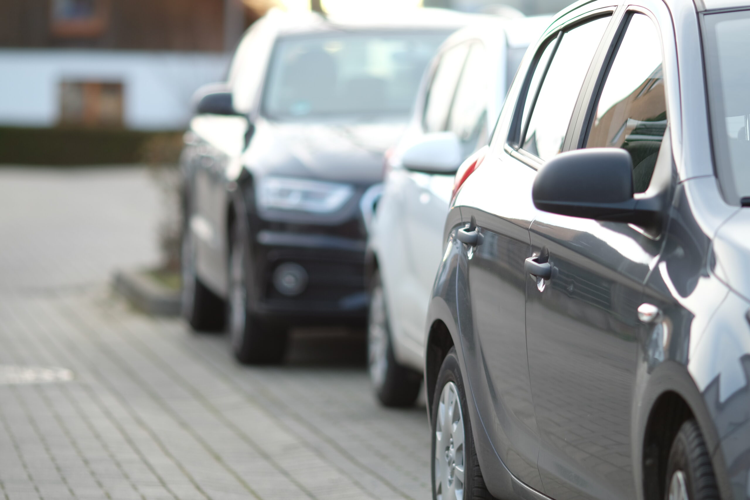 Inquadratura ravvicinata di una macchina nera nel parcheggio con uno sfondo sfocato.