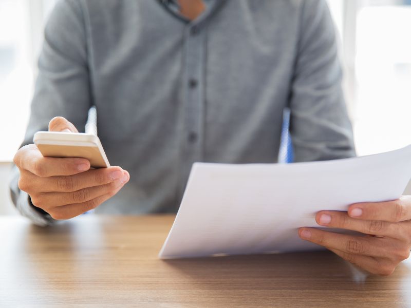 Uomo che legge un documento e invia un messaggio