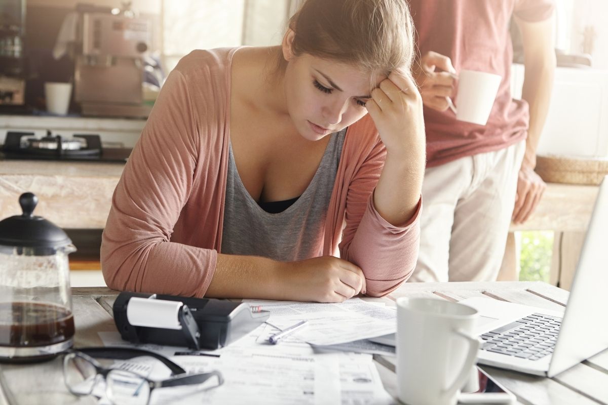 Giovane donna casual con espressione depressa mentre gestisce le finanze familiari